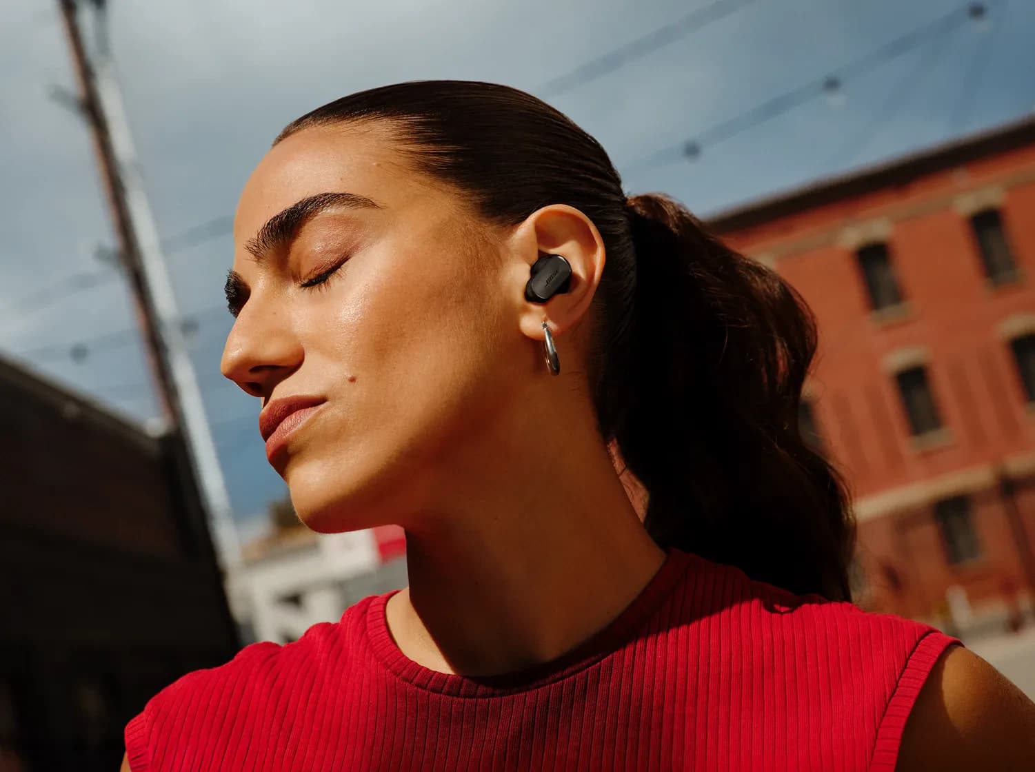 A woman wearing Bose QuietComfort Ultra Earbuds (2nd Gen) outdoors