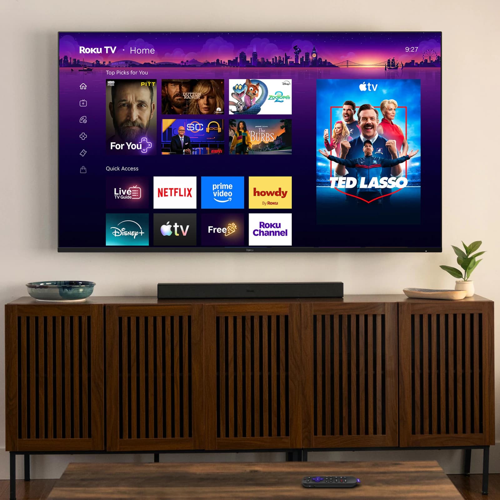 Roku Pro Series Mini-LED TV wall-mounted above a wooden media console
